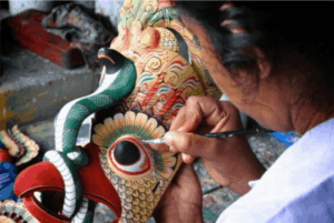 Artist painting the final touches on a carved mask