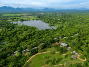 Aerial view of Ayugiri's suites surrounded by forest, with a lake in the background. 